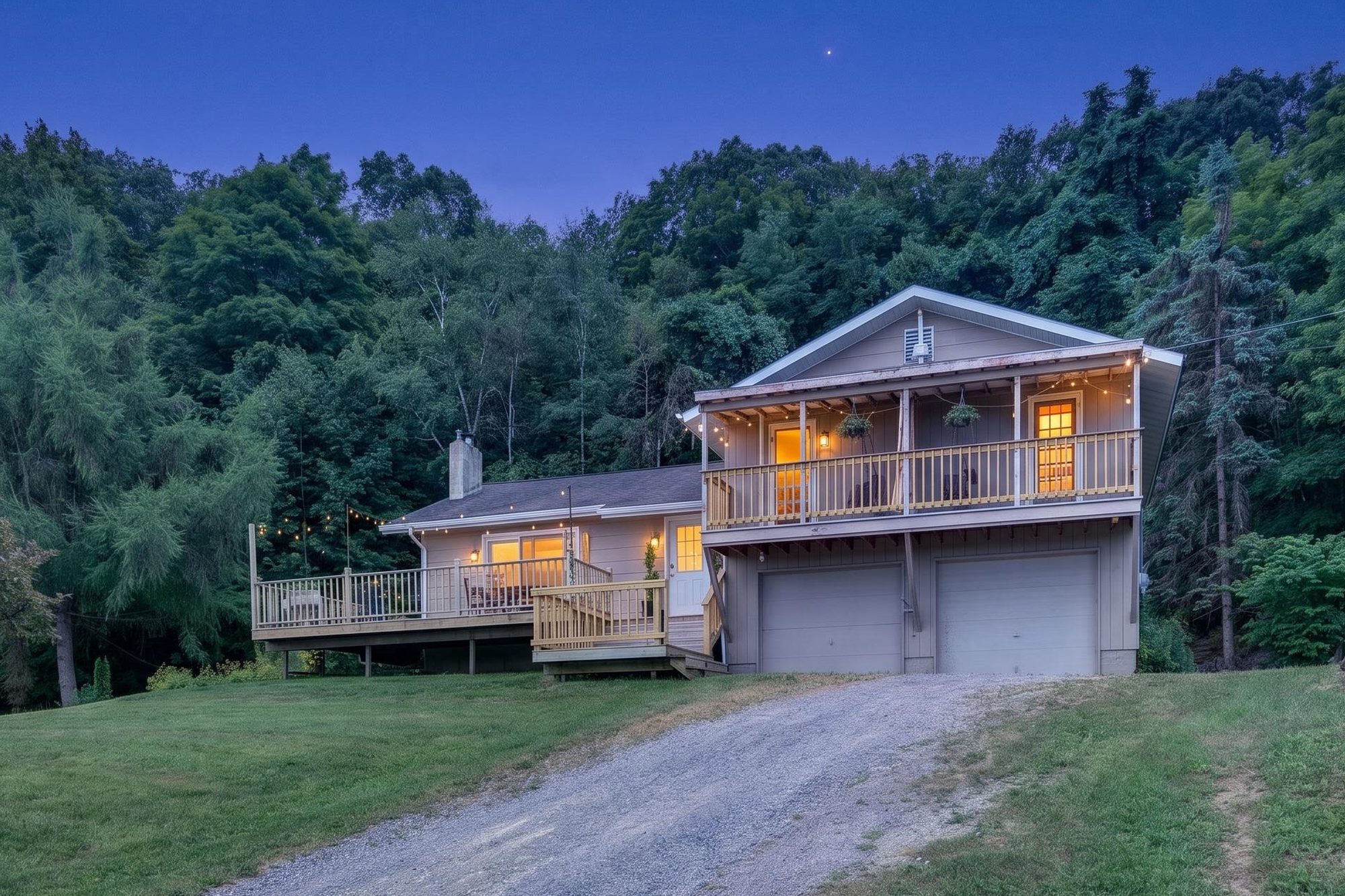 The house at blue hour with warm lights and string lights on the porch