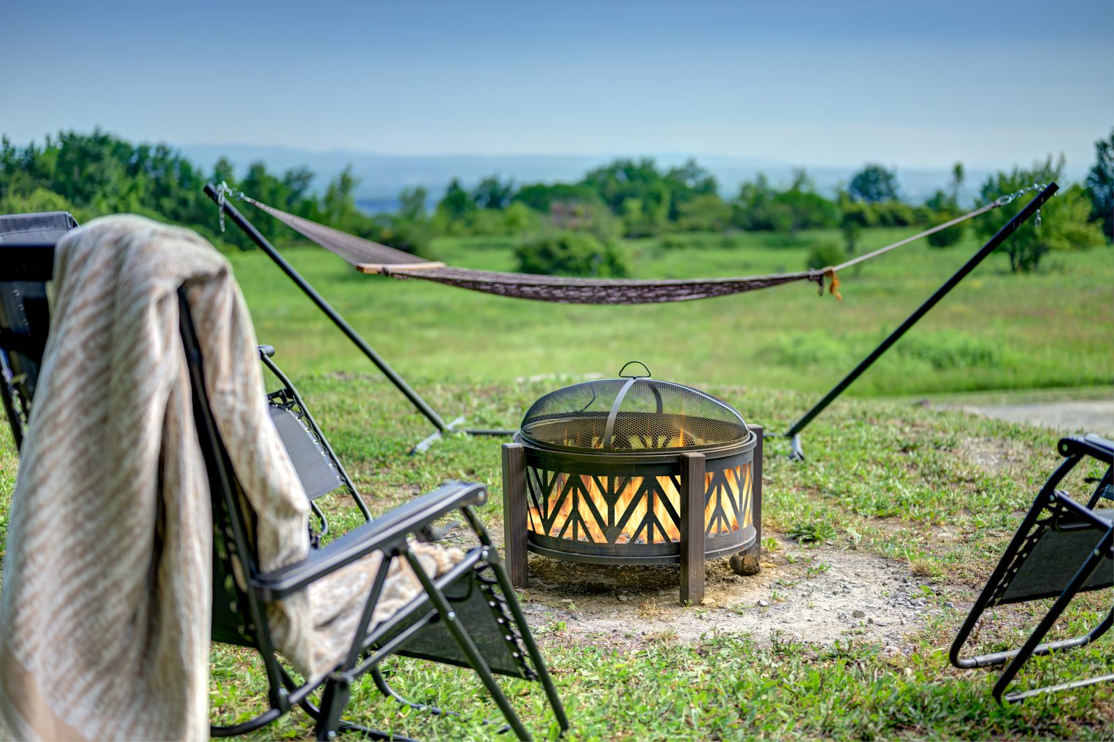 Fire ring with chairs and a hammock, valley beyond